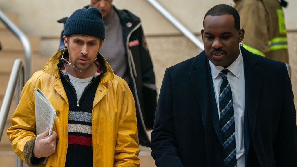 A promotional still from the film shows on the left Gosling as Ryland Grace and on the right Lionel Boyce as security guard Carl as they walk down a set of stairs during the film.