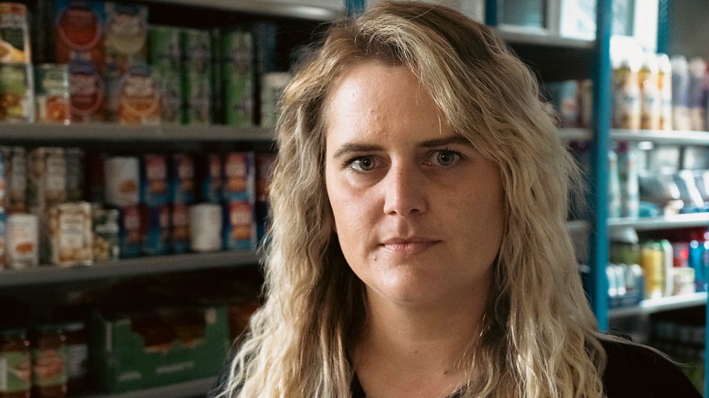 Kelly looking at camera in front of food shelves