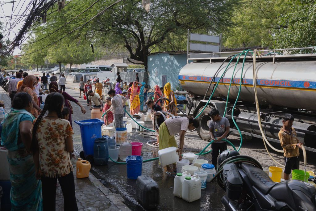 Families fill up empty water buckets with potable water from a New Delhi Municipal Council water tanker on May 02, 2024