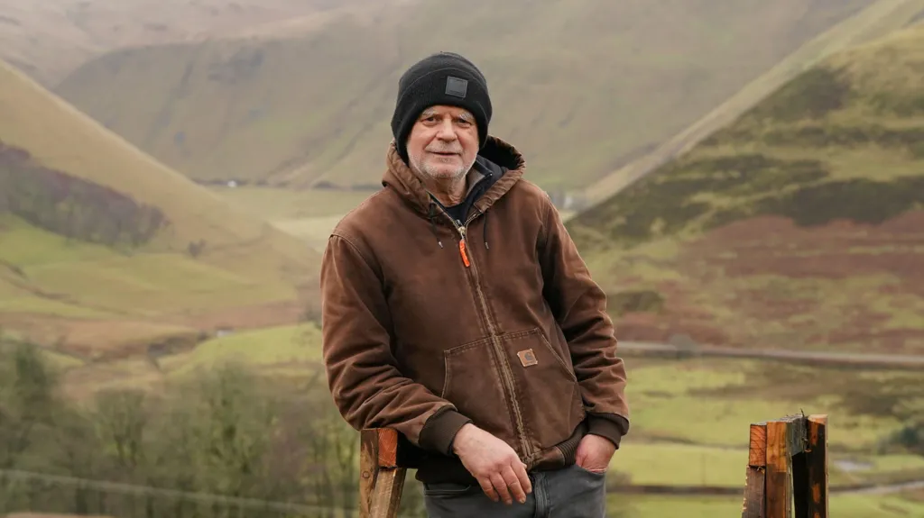 Andy Goldsworthy in hat looking to camera in countryside