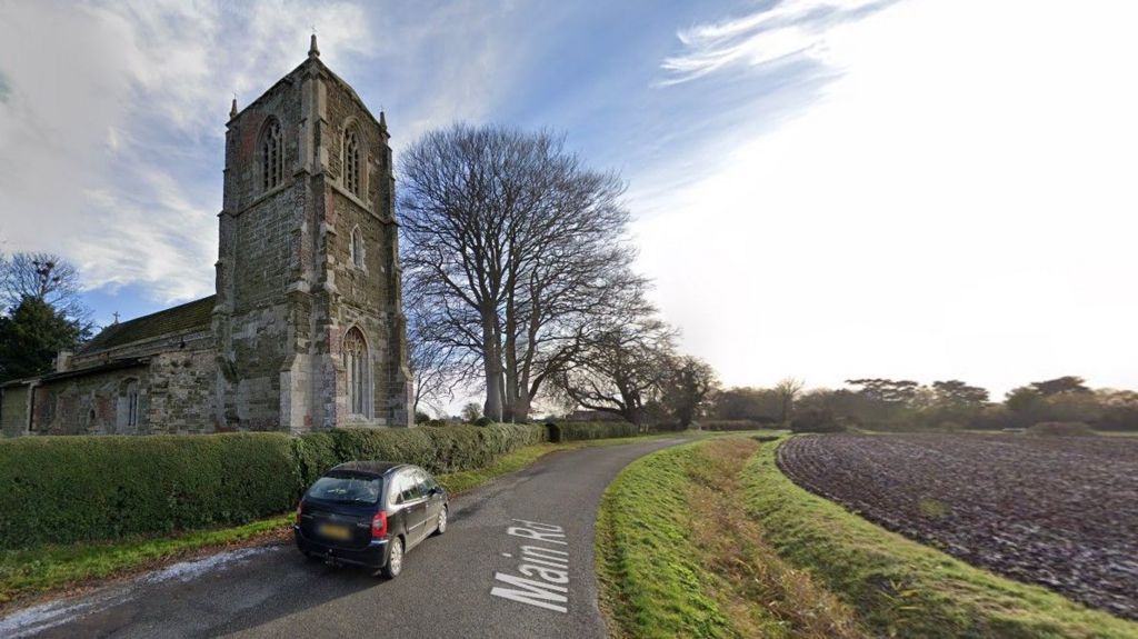 St Andrew's Church in Little Steeping, there is a country lane and a field next to it 