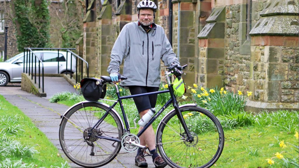 Nigel Brown, the organist outside the church with his bike 