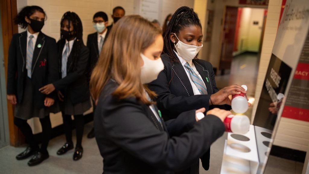 Year eight pupils wearing face masks sanitise their hands in a corridor at Moor End Academy in Huddersfield, on September 11, 2020.