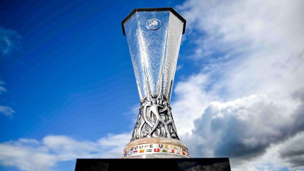 The Europa League trophy sits on a black pedestal with a blue sky behind