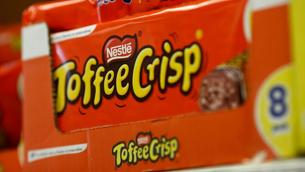 A close-up image of a bright orange box of Nestle Toffee Crisp bars on display in a shop