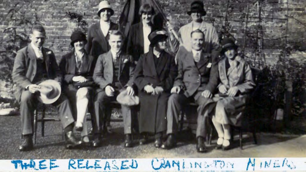 A black and white photograph of three of the miners held responsible for the derailment, following their release from prison - with their wives and mothers