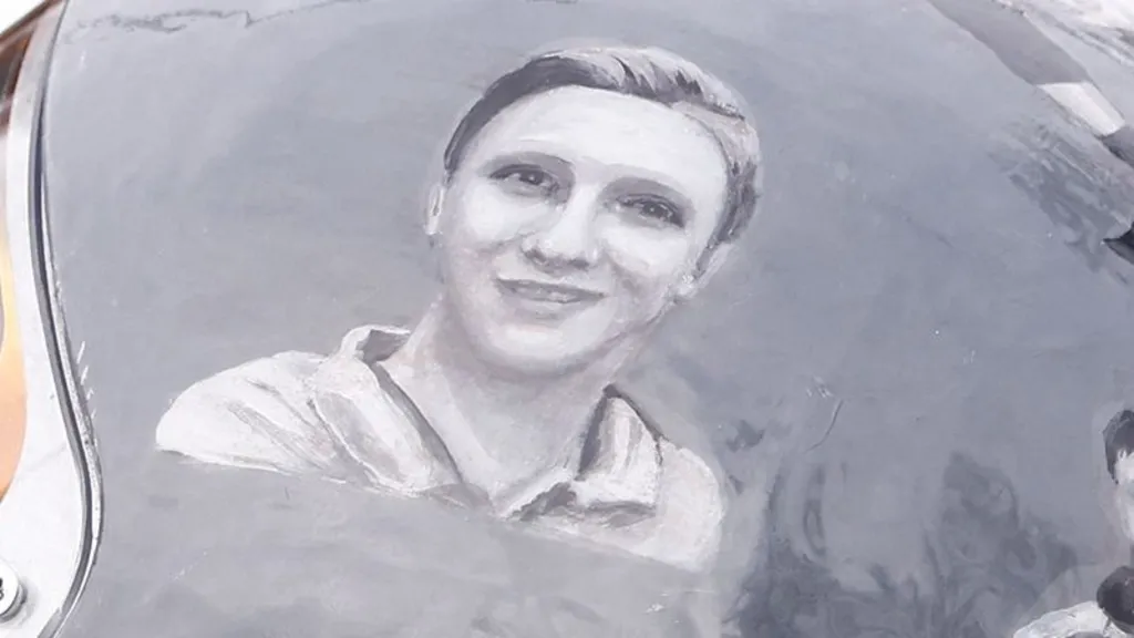 A close up of the helmet with a black and white illustration of Mykyta Kozubenko, who has short hair and is smiling.