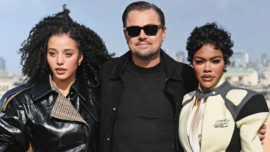 Chase Infiniti, Leonardo DiCaprio and Teyana Taylor attend the London photocall for One Battle After Another in London in September. Infiniti is wearing a black shiny jacket, DiCaprio has a black jacket and T-shirt on and Taylor has on a racing-style cream, grey and black jacket.