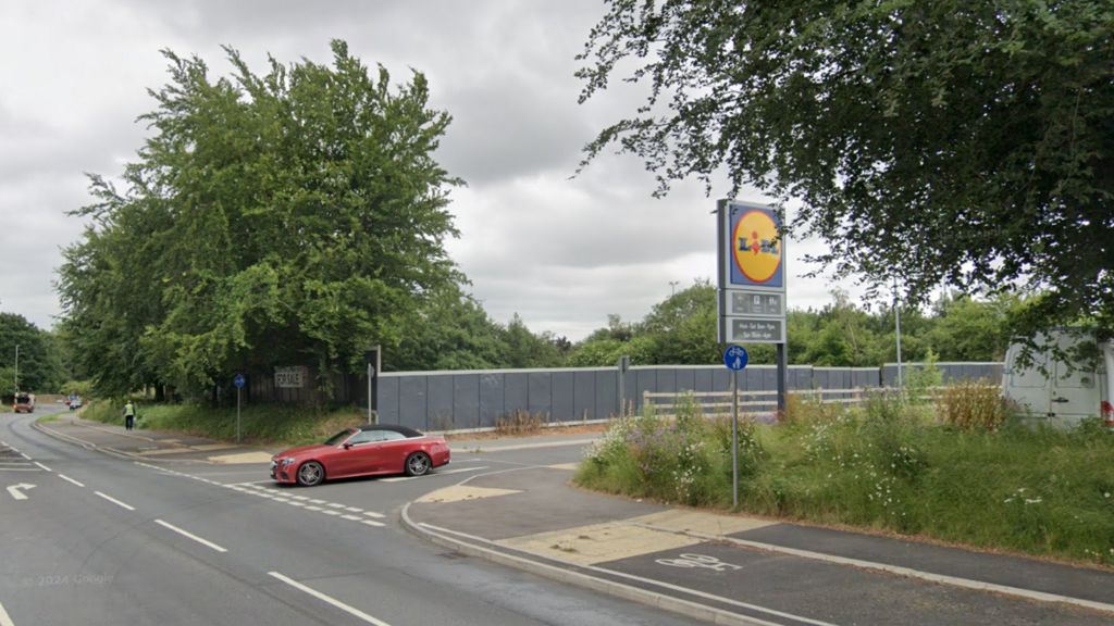 The Lidl sign and the site opposite the supermarket, with a car leaving the access road