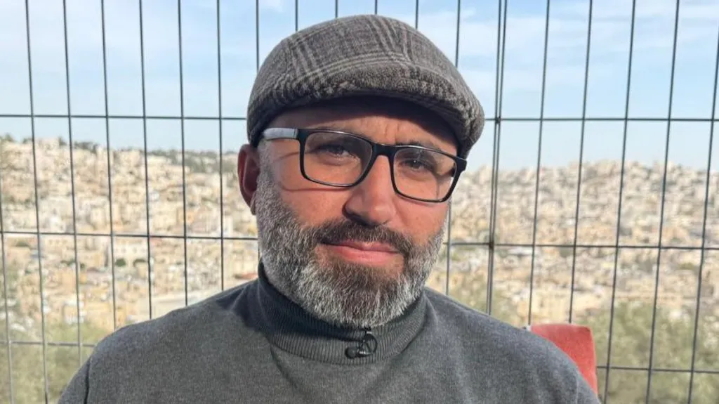 Palestinian activist Issa Amro stands inside his garden. Behind him is a view of Hebron, in the occupied West Bank