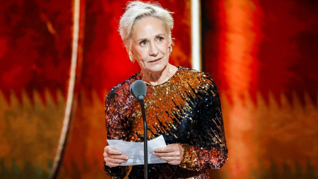 Laurie Metcalf at The 79th Annual Tony Awards, accepeting her acting prize while wearing an orange, black and brown sequined dress