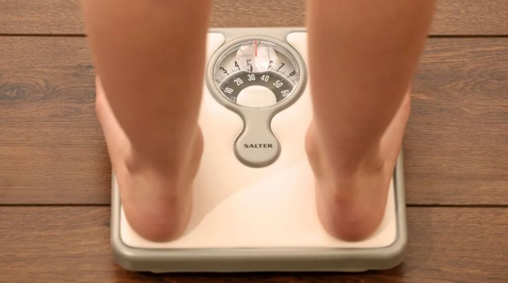 A pair of bare feet standing on a set of weighing scales