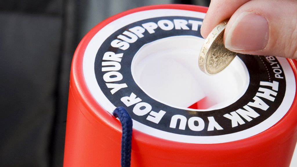A pound coin is put into a charity collection box