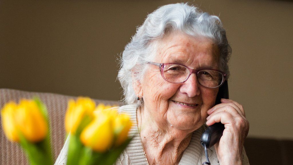 Stock image of an elderly woman using a landline phone