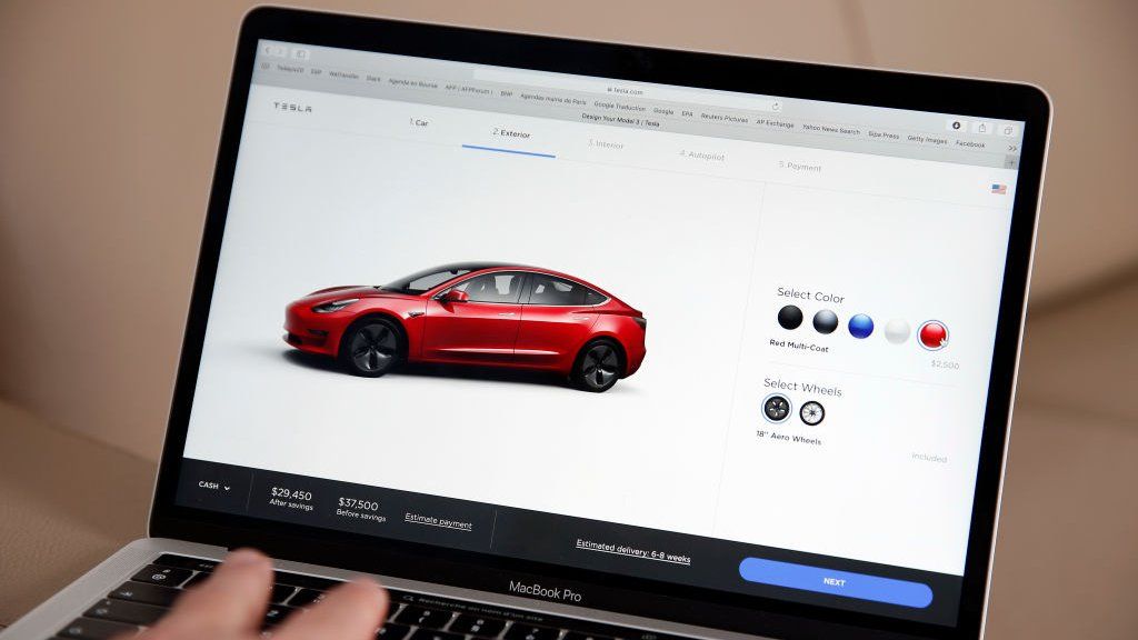 the Tesla website showing the Tesla 3 model is displayed on the screen of a laptop