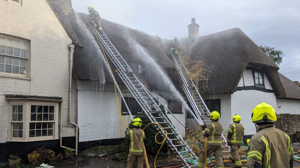 Firefighters putting out the thatch fire