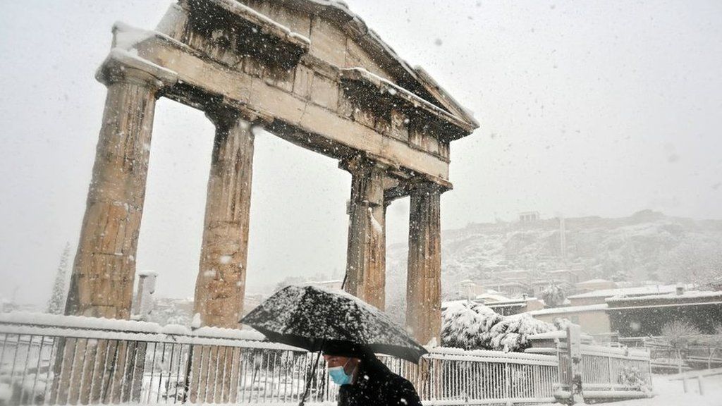 A man holding an umbrella in snow near the Roman Agora in central Athens