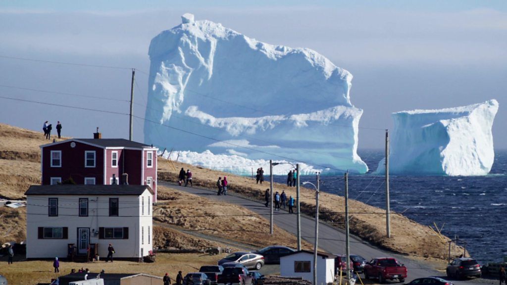An iceberg behind buildings.
