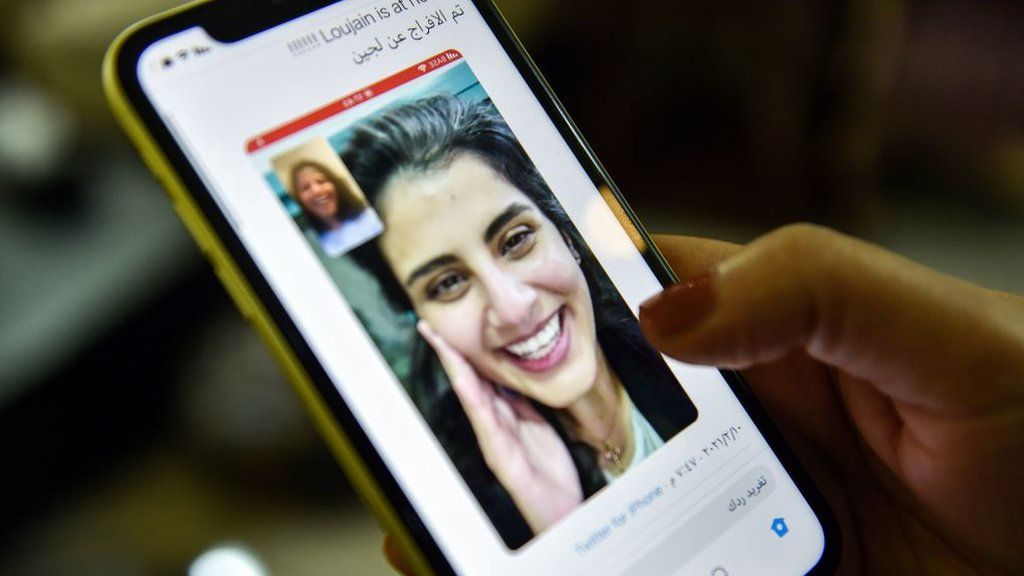A woman looks at a tweet posted by the sister of Saudi activist Loujain al-Hathloul, showing a screenshot of them having a video call following her release from prison (10 February 2021)
