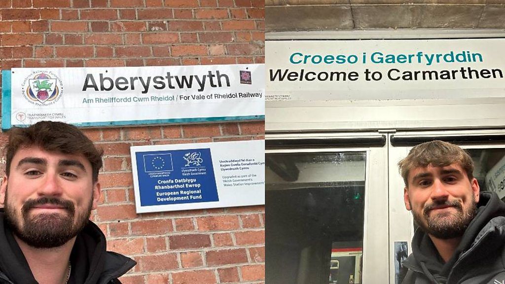 Jared Evitts in Carmarthen and Aberystwyth in front of two signs