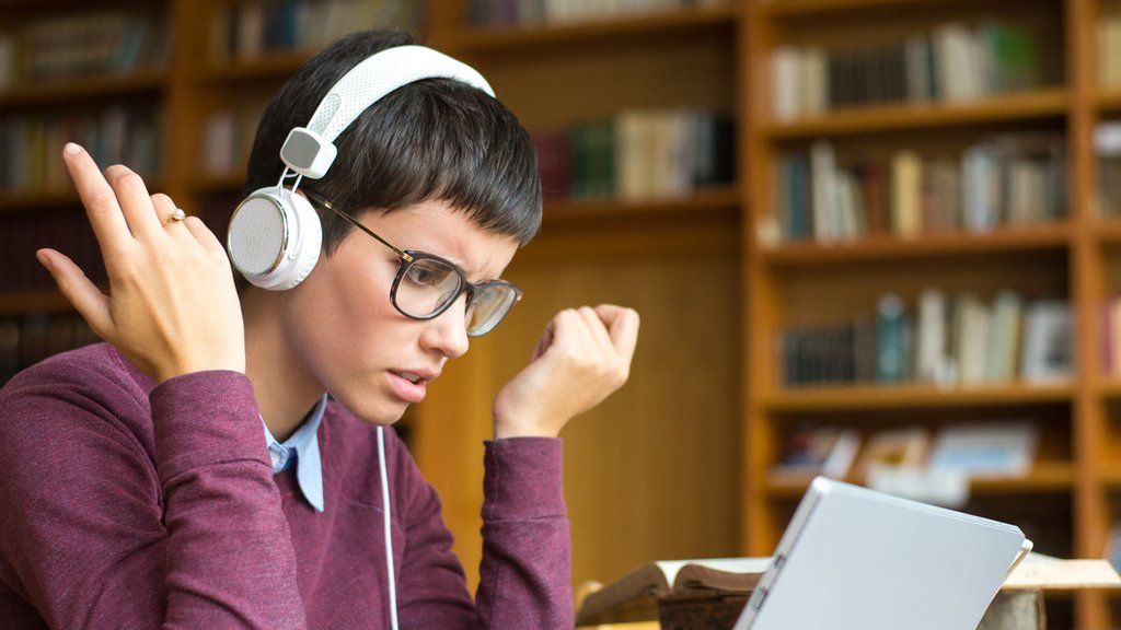 A young woman listening on headphones and annoyed.