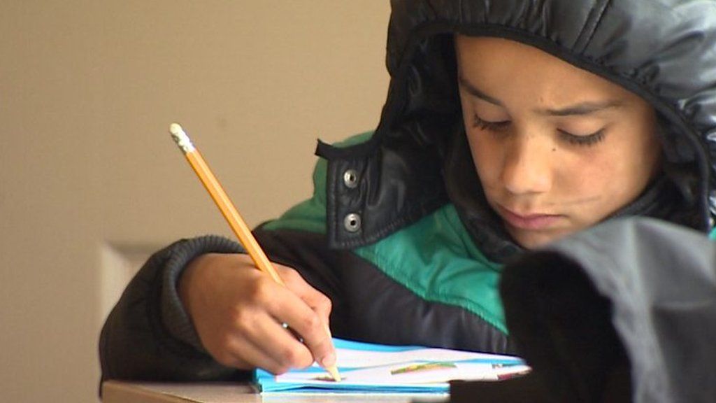 Child refugee writes in a book