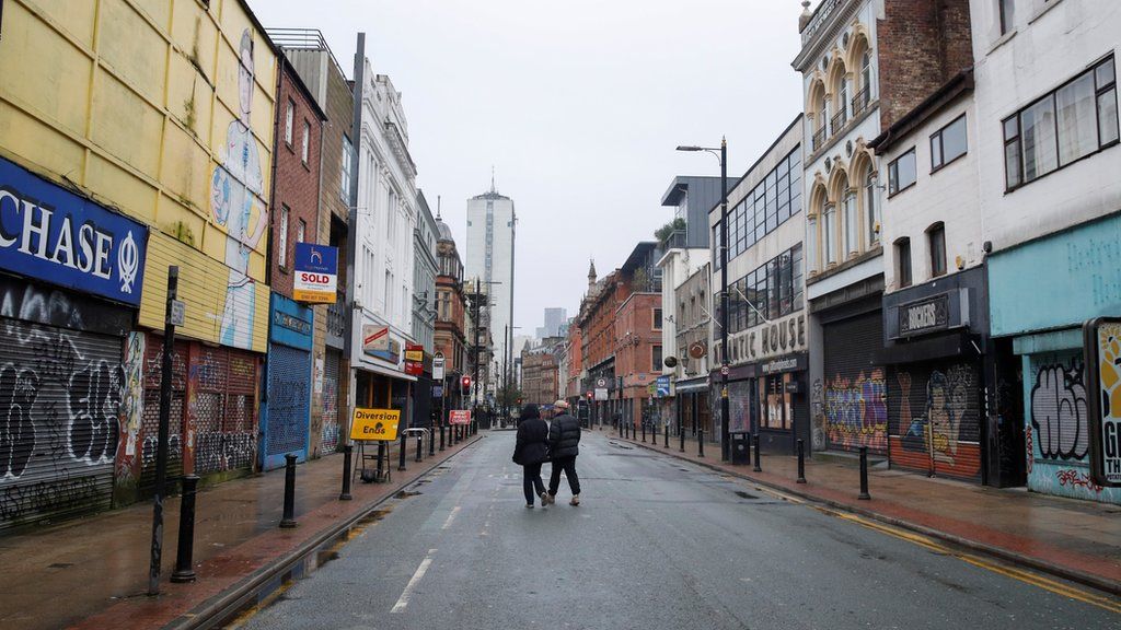 People walking down an empty street in Manchester