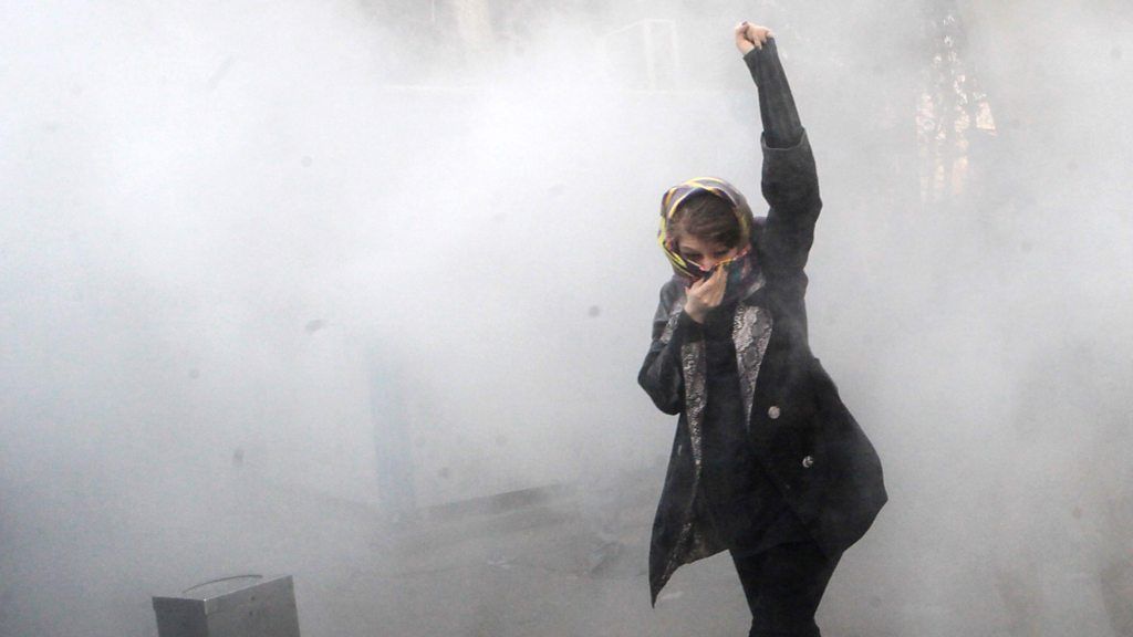 Iranian woman raises fist amid tear gas