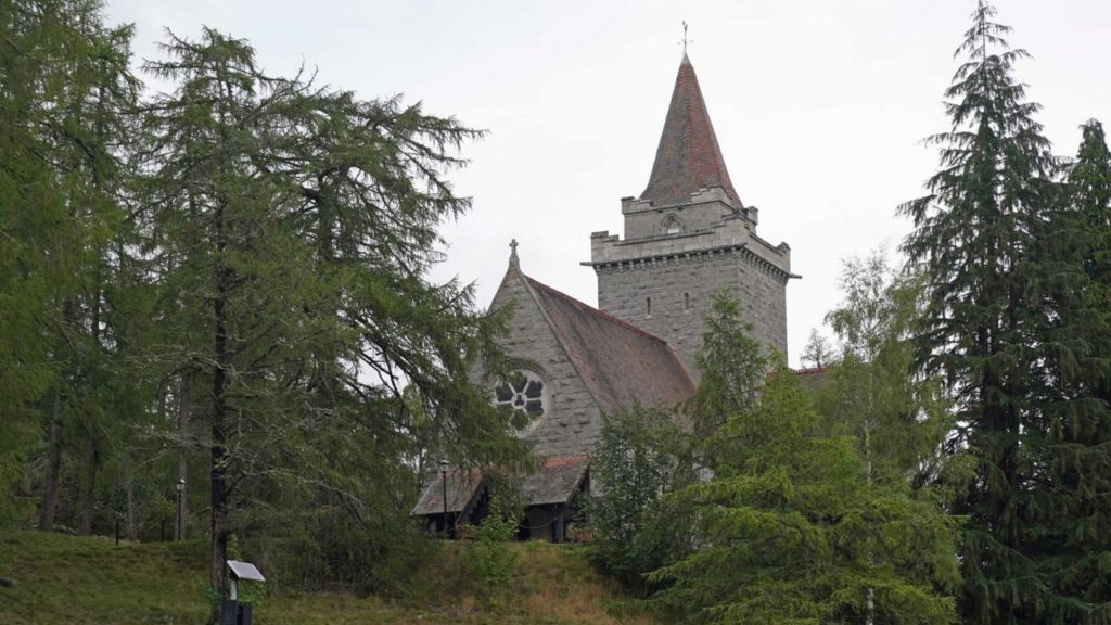 Church building with red tiled roof sits among trees