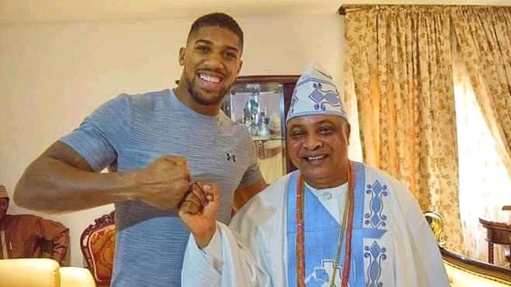 Anthony Joshua smiles as he bumps fists with a dignitary wearing traditional Nigerian clothing in the town of Sagamu