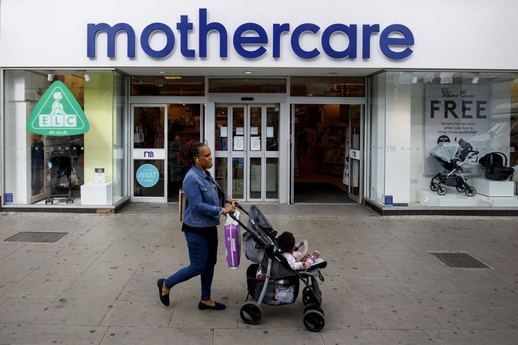 Woman with push chair walks past mothercare store