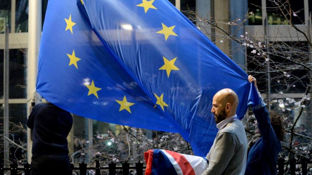 Workers replace the union jack flag outside the European Parliament building with the European Union flag, as Britain leaves the European Union
