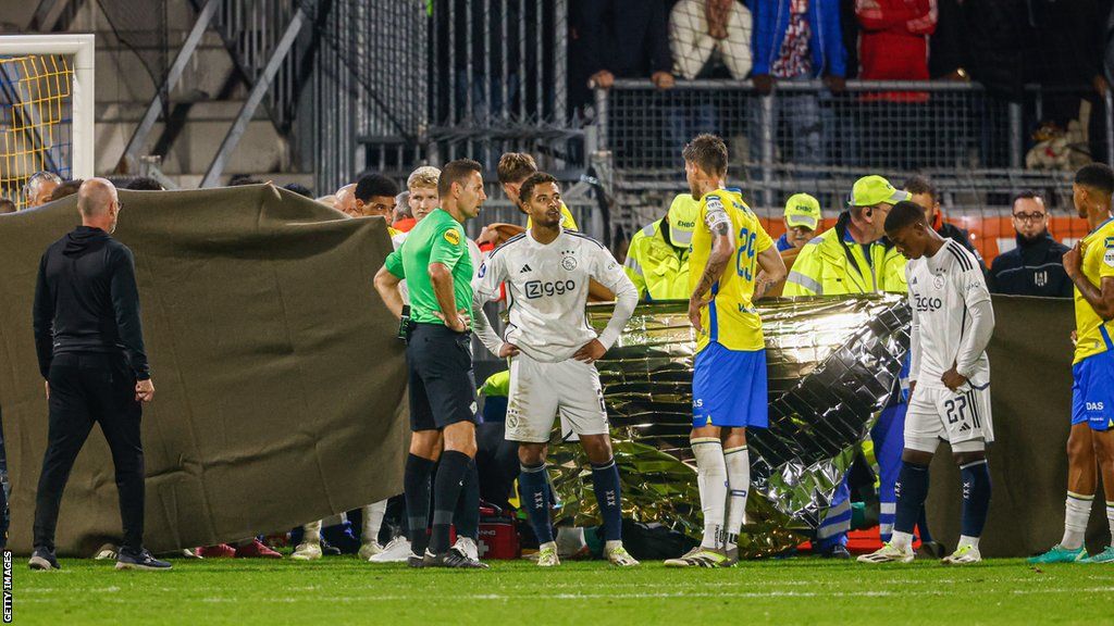 Players stand around Etienne Vaessen after head injury