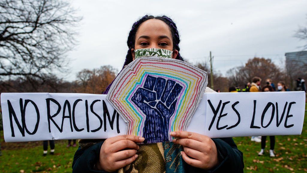 A Black woman is holding a placard in front of her against racism, during the demonstration against racism and extreme right-wing intimidation, in The Hague, on 6 December 2020
