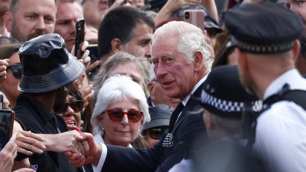 King Charles surrounded by people outside Buckingham Palace
