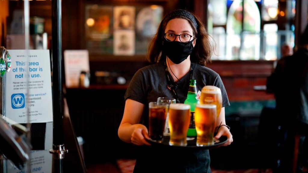 Pub worker serving drinks wearing a face covering