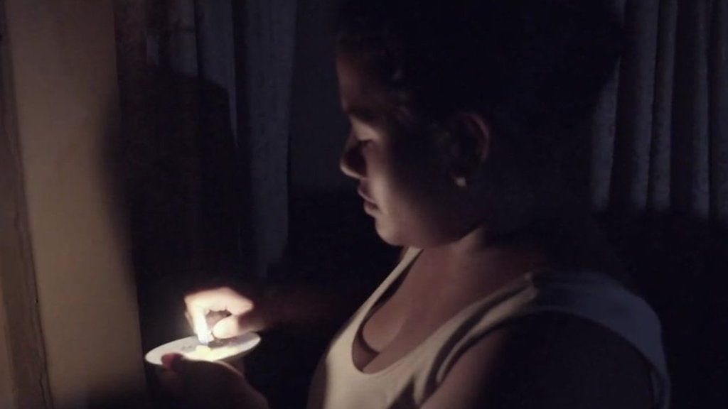 A woman holds a candle during a blackout in Venezuela
