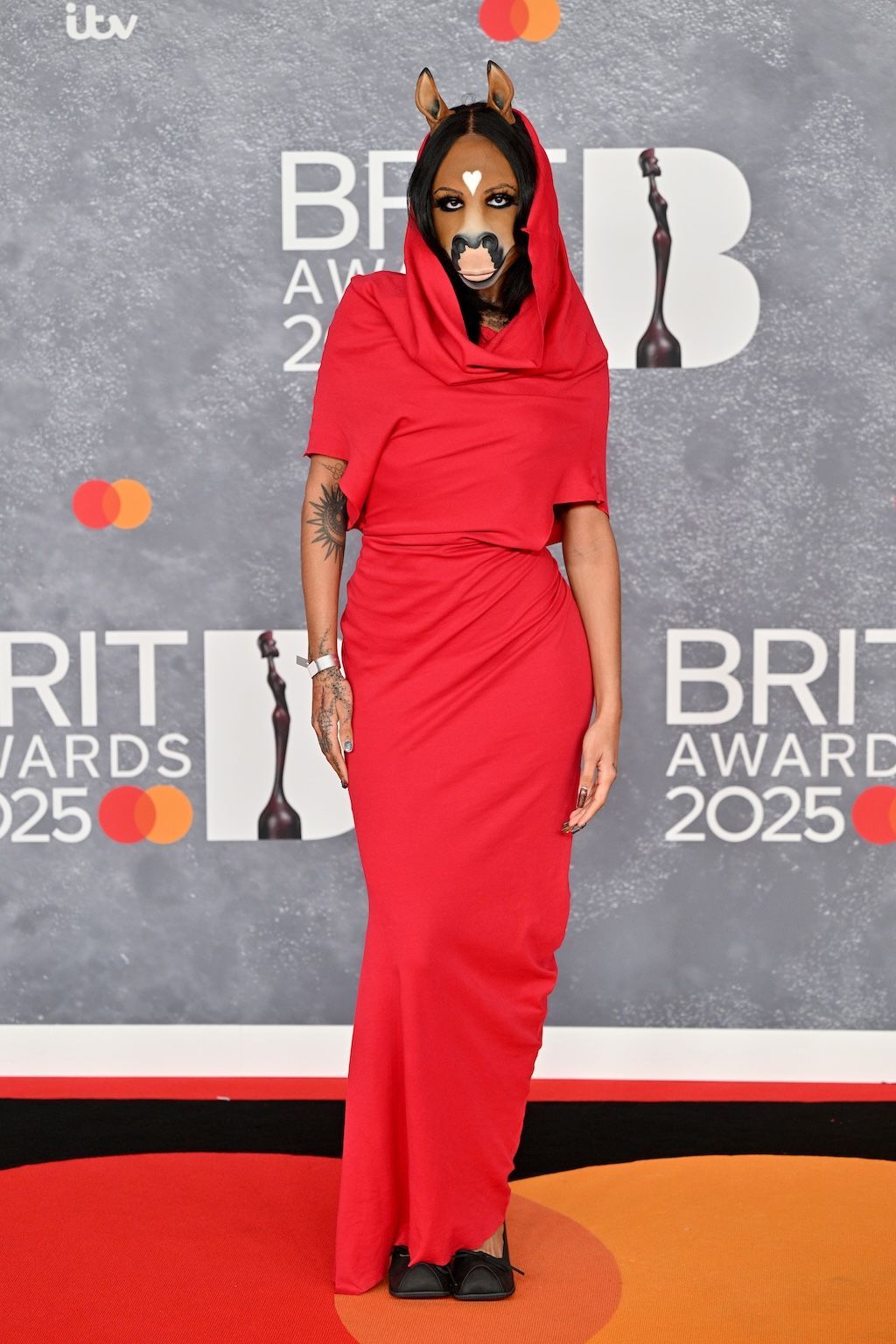 A woman with a facemask depicting a horse at the 2025 Brit Awards