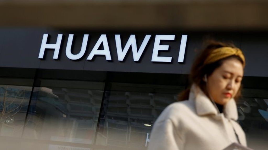 Woman walks past Huawei shop