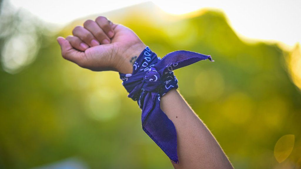 A woman wears a purple bandana round her wrist to mark International Women's Day