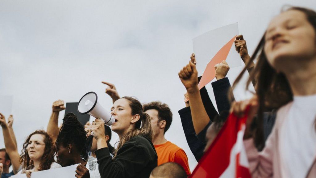 Ativistas com cartazes e megafone durante protesto