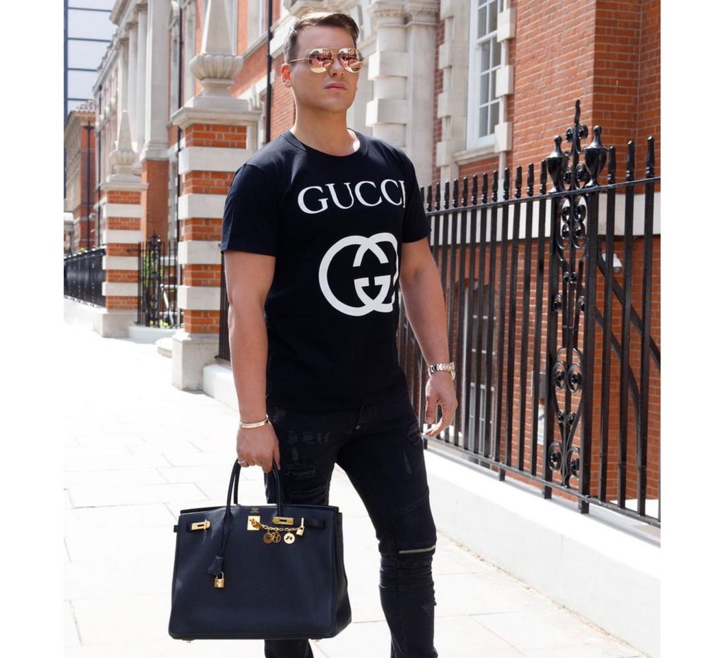 Israel Cassol photographed in the street with a Birkin designer handbag and a Gucci tshirt