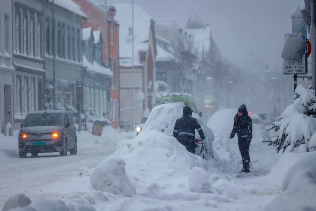 People remove snow from a car in Kristiansand, Norway, on 2 January.