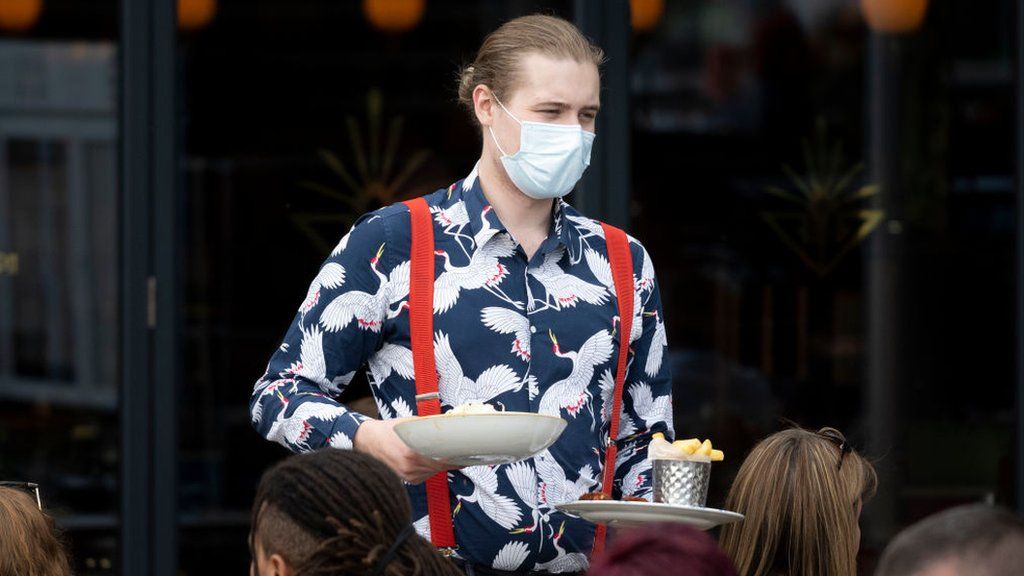 Waiter wearing a face mask.