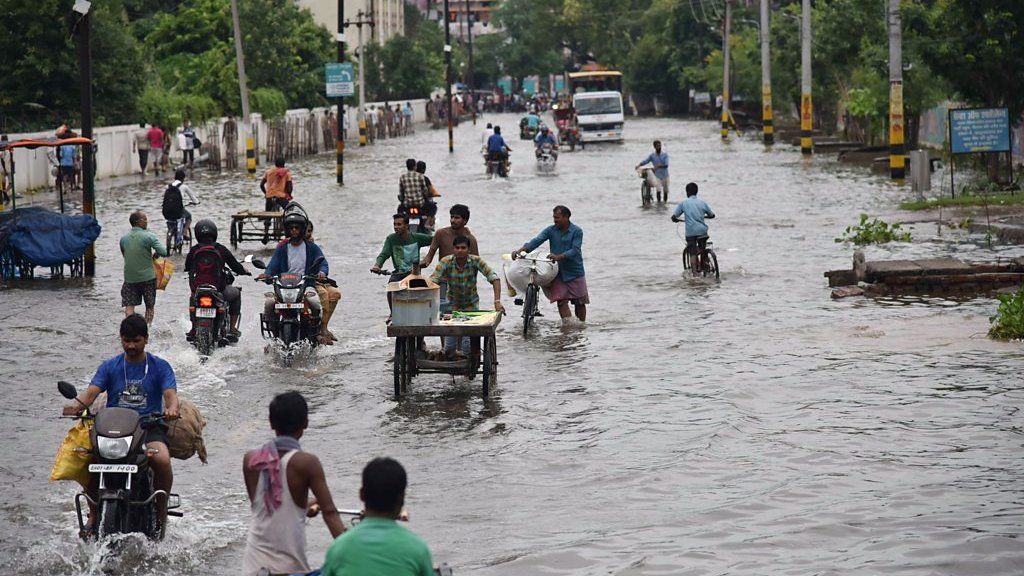 Commuters make their way on a waterlogged road following heavy monsoon rain in Patna