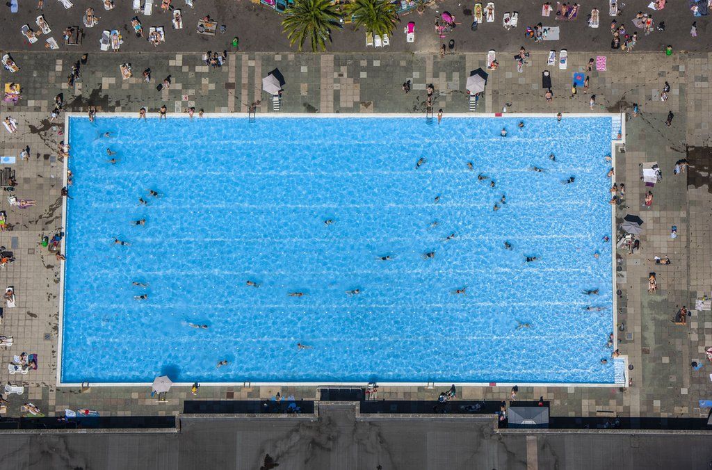 People swimming in the acrylic Sky Pool at Embassy Gardens in Nine Elms