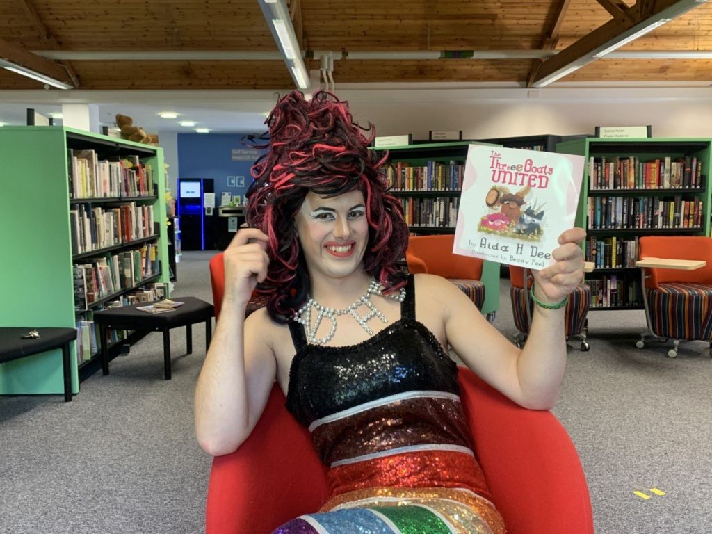 The Drag Queen, Aida H Dee, holds her book smiling after a Drag Queen Story Hour event in Cowbridge
