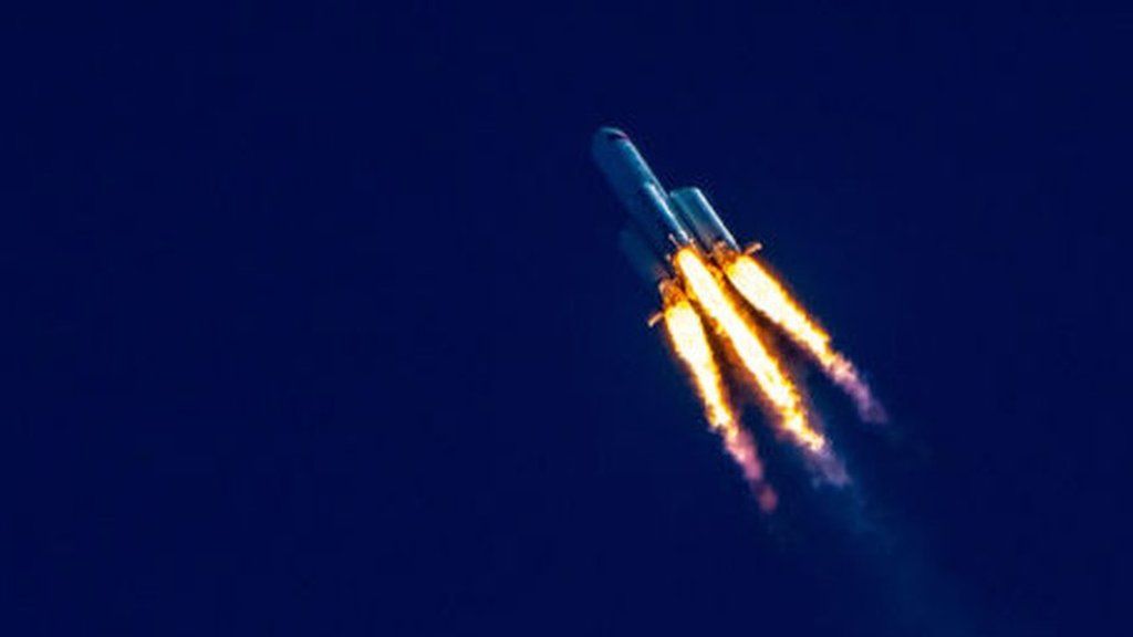 rocket flying diagonally with flames in front of dark blue sky