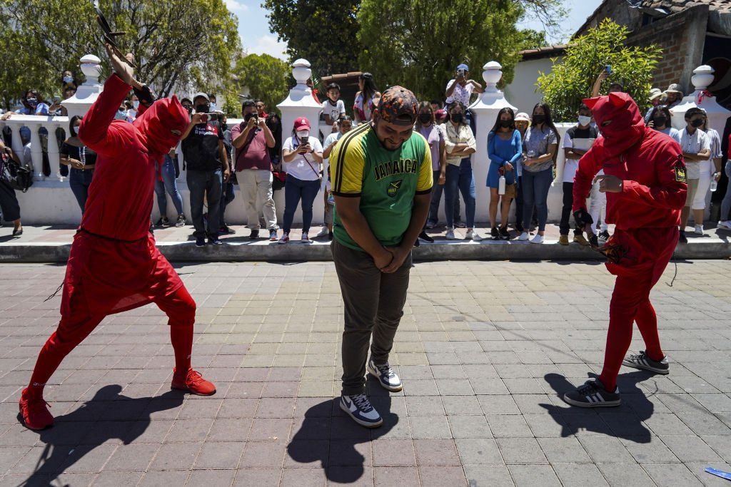 Revellers dressed as devils whip a faithful during the celebration of the "Talciguines" of Texistepeque on April 11, 2022