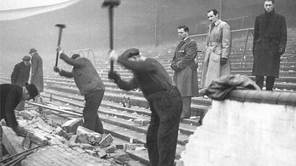 Workmen repair the broken terracing wall at Shawfield in 1957